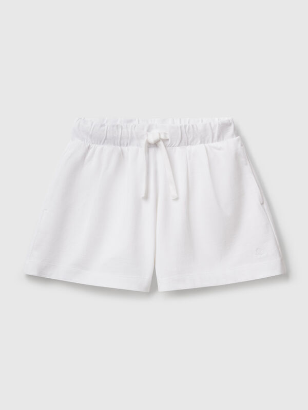 Pantalón corto de puro algodón de tacto cálido. Cintura con cordón, bolsillos insertados en los laterales y logo bordado en el bajo izquierdo. Perfecto para outfits cotidianos. Niña